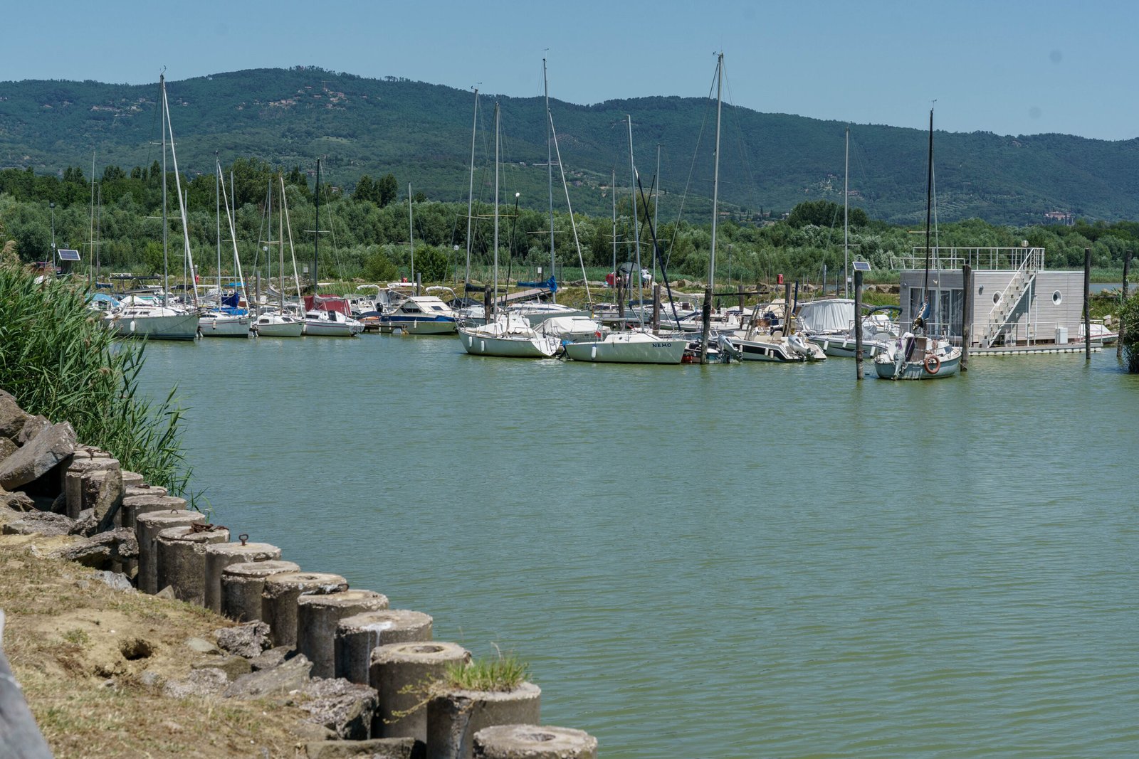Small marina with sailing boats on a lake surrounded by hills