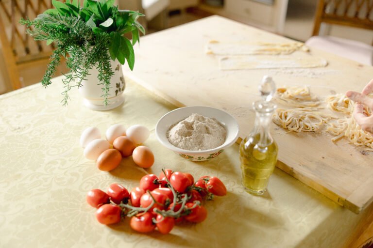 Villa Cortona Woman preparing fresh pasta at a table under a garden pergola