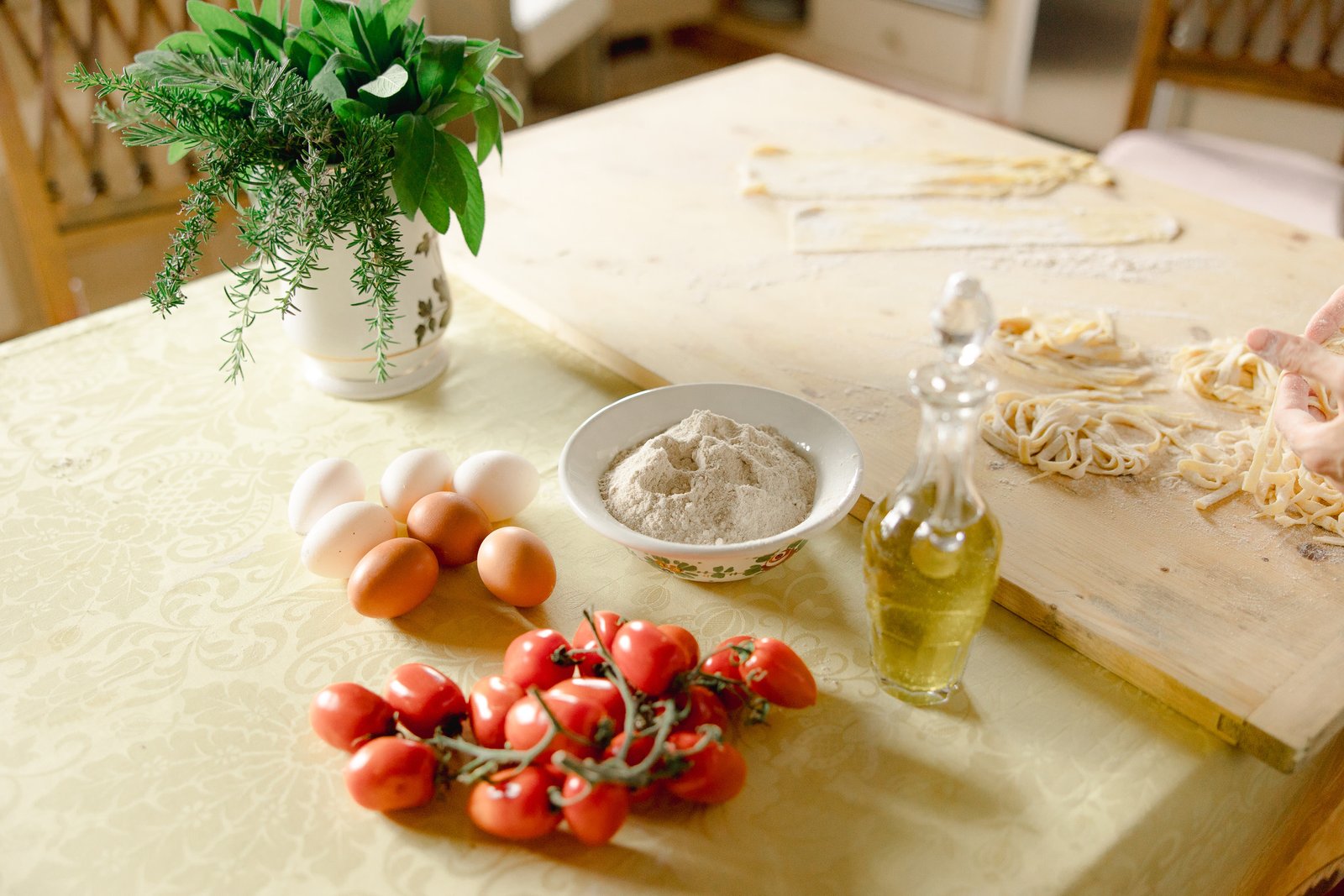 Woman preparing fresh pasta at a table under a garden pergola
