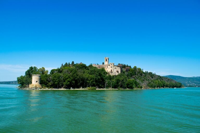 Lago Trasimeno Calm lake with a wooded island and hills in the distance