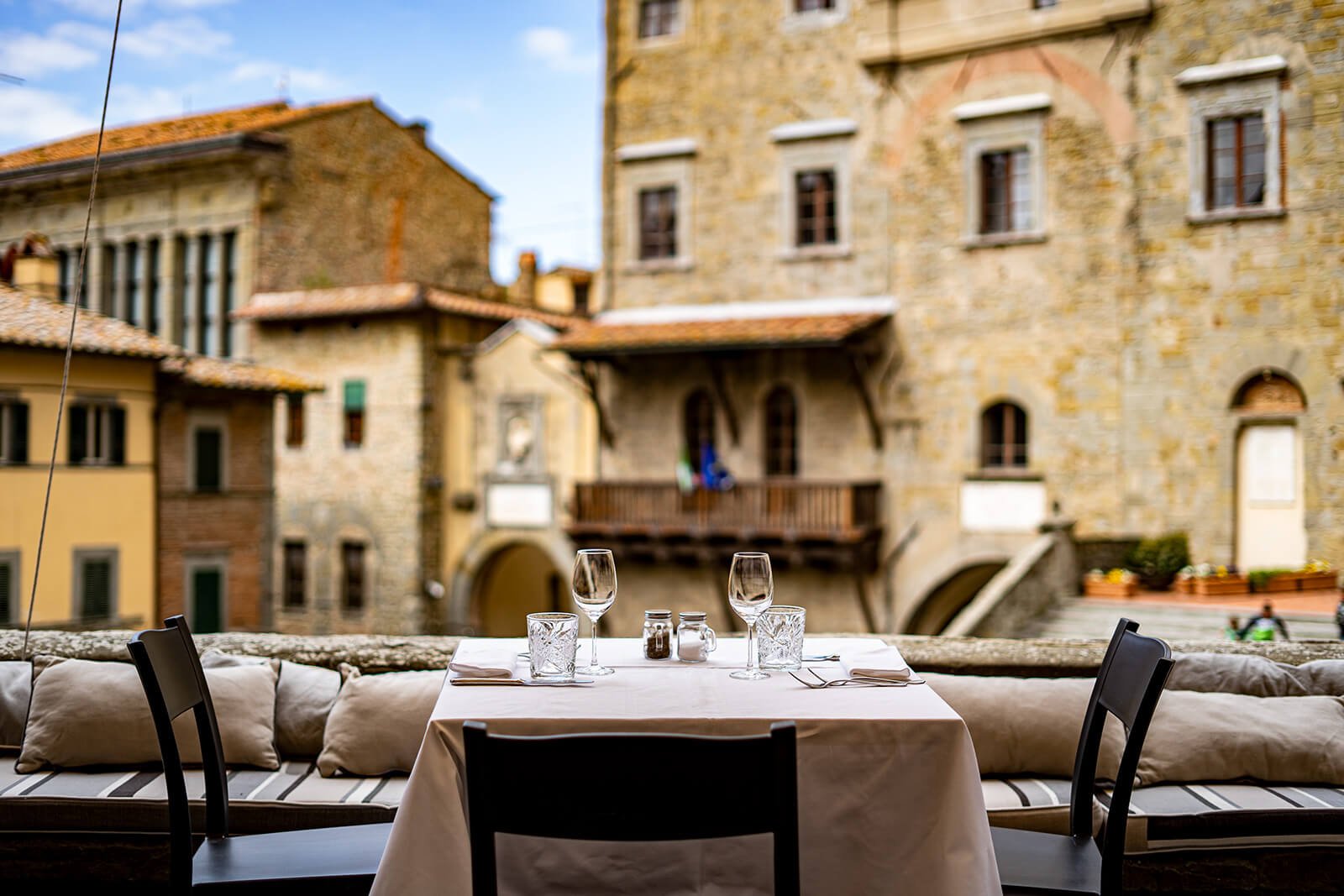 Table set outdoors at Ristorante La Loggetta, overlooking a stone piazza in Cortona