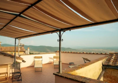 Covered terrace with deckchairs and panoramic view over the Tuscan countryside at Cortona Charme apartment, Cortona