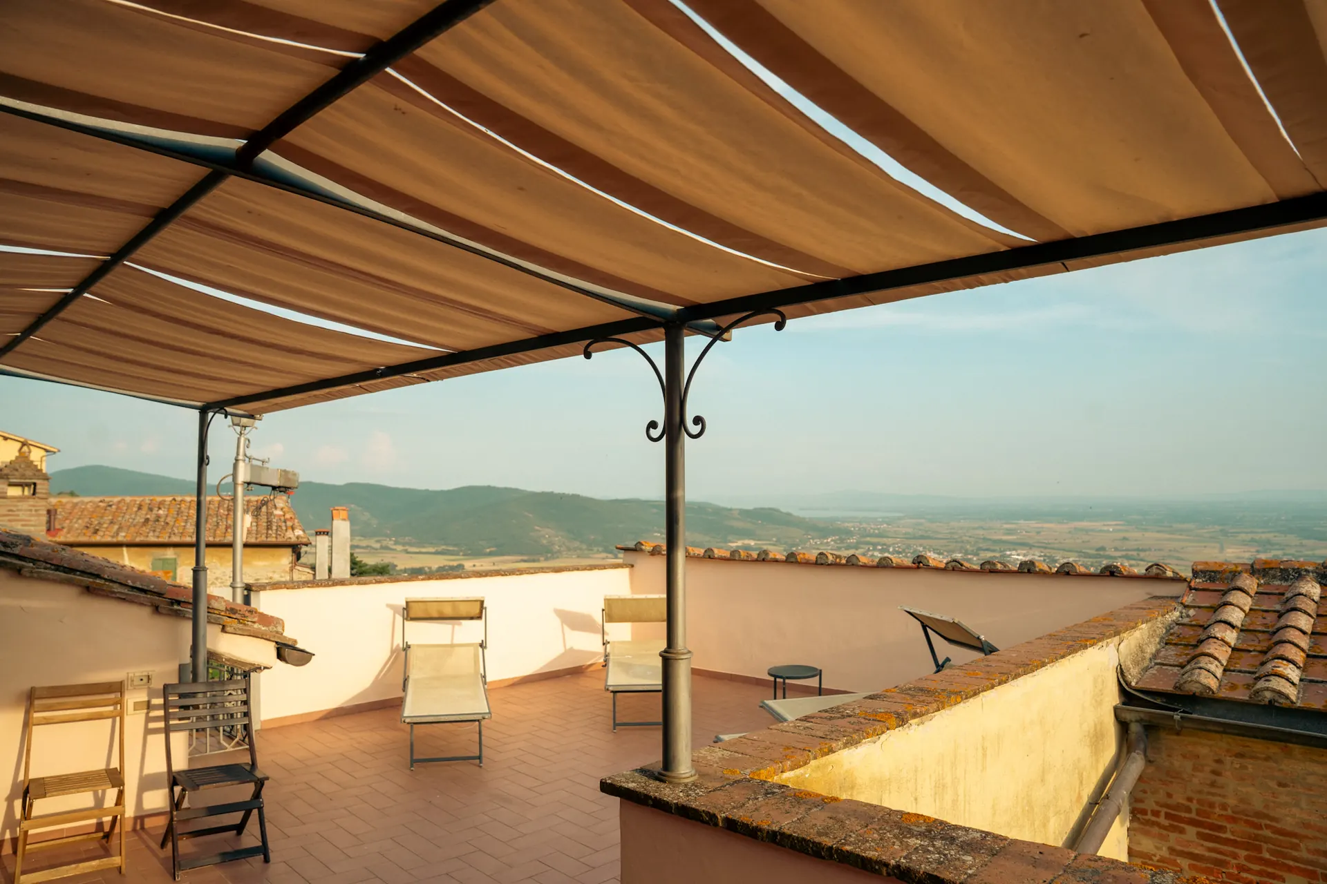 Covered terrace with deckchairs and panoramic view over the Tuscan countryside at Cortona Charme apartment, Cortona