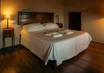 Cosy double bedroom with antique wooden headboard and parquet floor at Cortona Charme apartment in Cortona old town