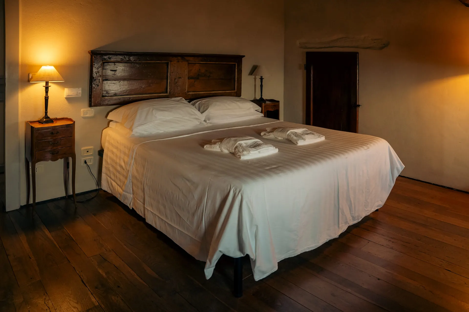 cortona-charme-apartment-double-bedroom-wooden-floor Cosy double bedroom with antique wooden headboard and parquet floor at Cortona Charme apartment in Cortona old town
