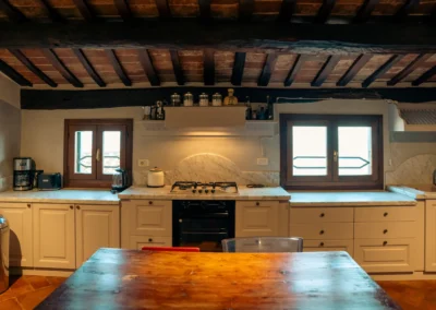 Fully equipped kitchen with wooden-beam ceiling and dining table at Cortona Charme apartment, Cortona