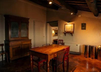Living and dining room with antique cupboard, wooden table and beamed ceiling at Cortona Charme apartment, Cortona