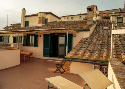 Private rooftop terrace with sun loungers and outdoor table among the terracotta roofs of Cortona at Cortona Charme apartment