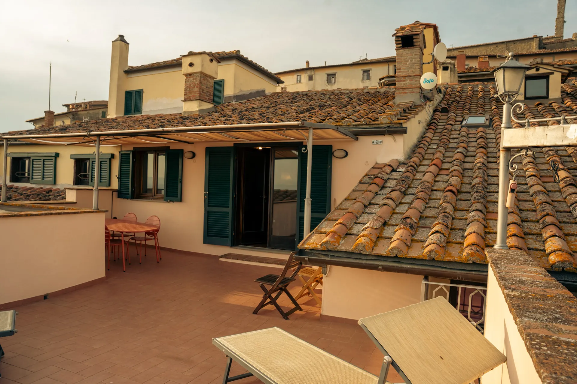 cortona-charme-apartment-rooftop-terrace-sun-loungers Private rooftop terrace with sun loungers and outdoor table among the terracotta roofs of Cortona at Cortona Charme apartment
