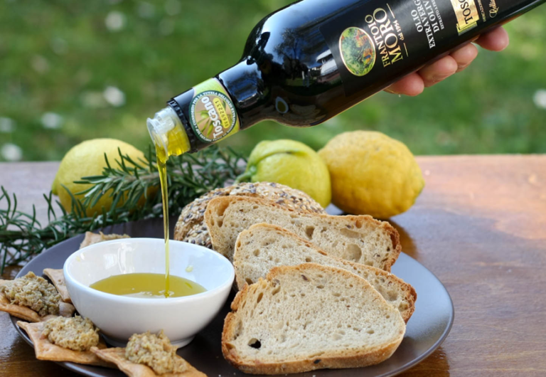New olive oil poured into a bowl beside toasted bread and lemons New olive oil poured into a bowl beside toasted bread and lemons