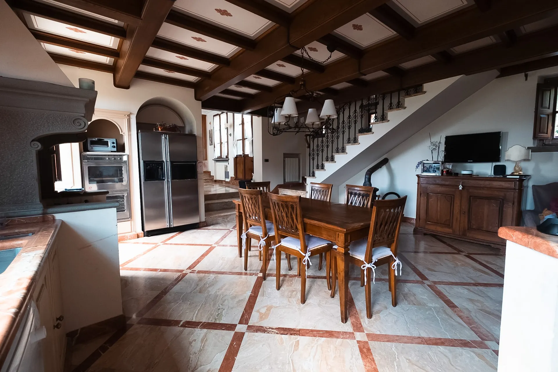 in-villa-house-cortona-open-plan-kitchen-dining-beamed-ceiling Open-plan kitchen and dining area with wooden-beam ceiling and marble floors at In-Villa House, Cortona