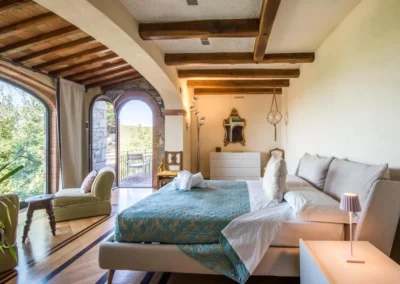 Double bedroom with beamed ceiling and arched glass door opening onto a terrace at Villa Erbolino, Chianti