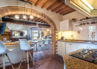 Rustic kitchen with breakfast bar and brick arch opening onto the dining room at Villa Erbolino