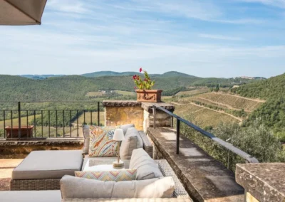 Terrace lounge with outdoor sofas overlooking vineyards and the rolling Chianti hills at Villa Erbolino
