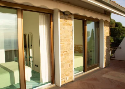 Bedroom with sliding glass doors opening straight onto the terrace and stone wall of the villa
