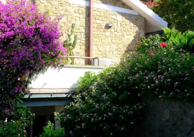 Purple bougainvillea and flowering shrubs against the stone walls of the villa