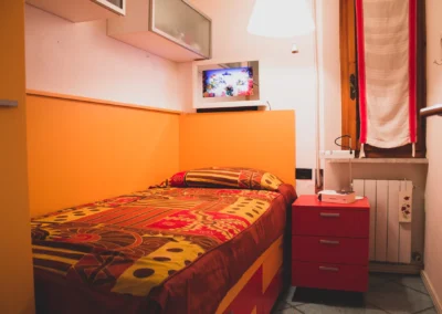 Cosy single bedroom with orange walls and a red bedside table at Villa Monte Bianco