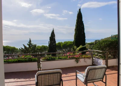 Two armchairs on the terrace of Villa Monte Bianco looking over pines and cypresses to the Tyrrhenian Sea