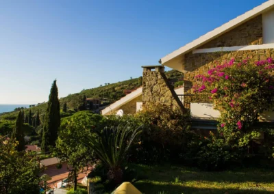 Stone villa with pink bougainvillea, cypresses and a glimpse of the sea on the hill of Castiglione della Pescaia