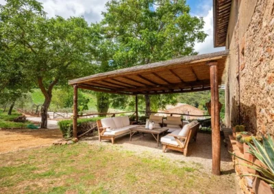 Wooden covered pergola with outdoor sofas in the shaded garden of the villa