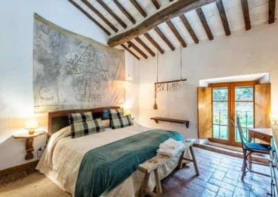 Double bedroom with beamed ceiling, terracotta floor and window onto the garden