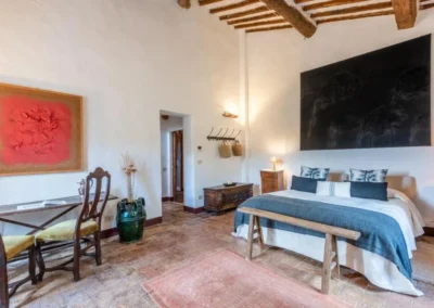 Spacious double bedroom with modern artwork, beamed ceiling and terracotta floor