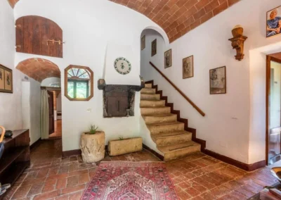 Entrance hall with terracotta staircase, brick vault, antique furniture and rug