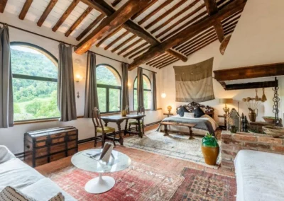 Large bedroom with high beamed ceiling, arched windows, sitting area and countryside views