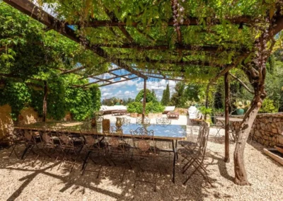 Long outdoor dining table for a large group under a vine-covered pergola at the villa near Monteriggioni