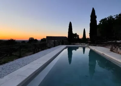 Long swimming pool at sunset with cypress silhouettes near Monteriggioni, Tuscany