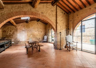 Hall with exposed stone walls, arches, beamed ceiling and large glass doors at the villa