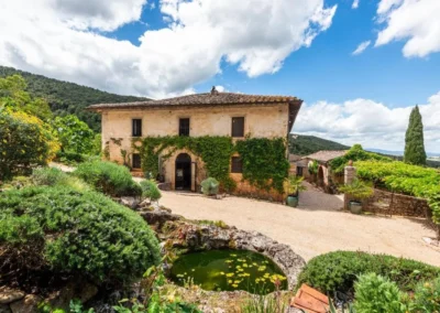 Ivy-covered stone villa with arched entrance, garden and lily pond near Monteriggioni, Tuscany