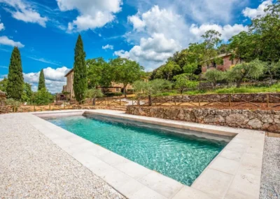 Swimming pool with stone surround, cypresses and Tuscan countryside near Monteriggioni