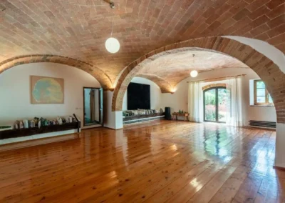 Spacious vaulted brick hall with wooden floor and arched French windows at the villa