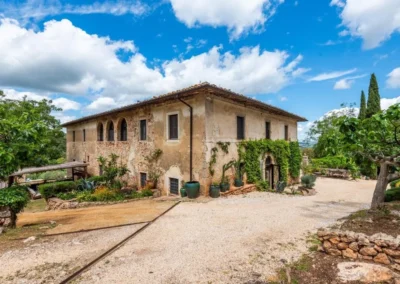 Historic stone farmhouse villa with arched loggia and gravel courtyard near Monteriggioni