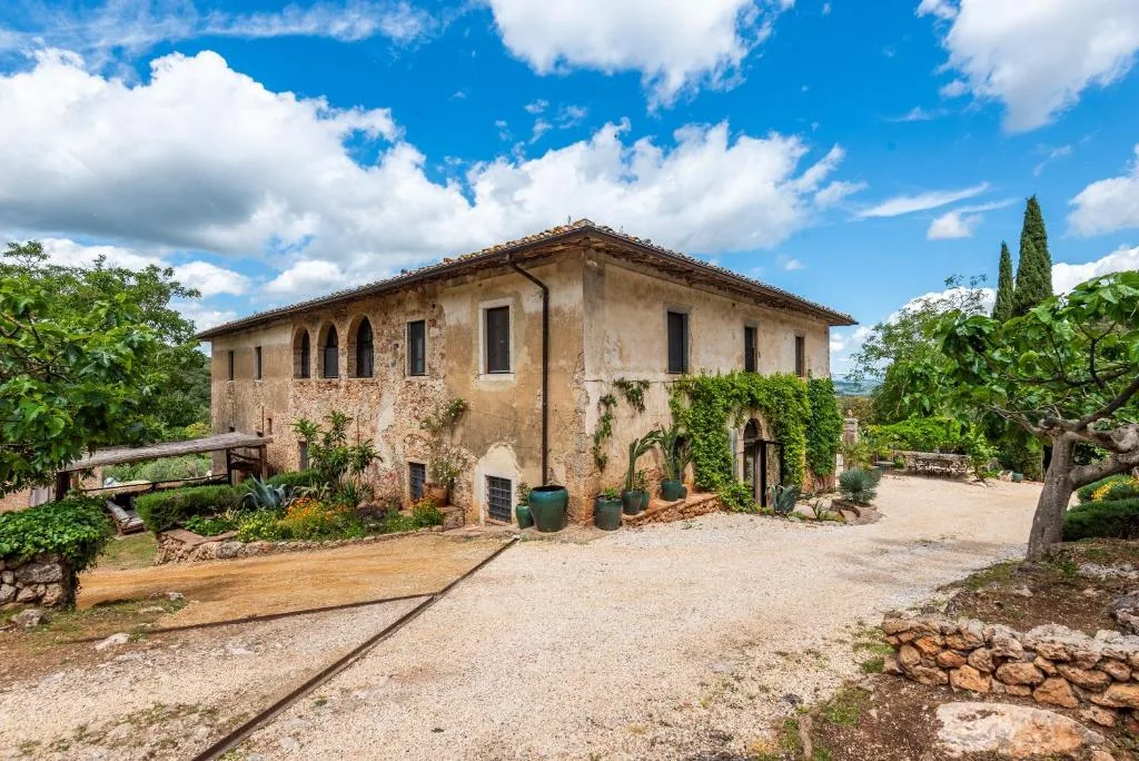Historic stone farmhouse villa with arched loggia and gravel courtyard near Monteriggioni