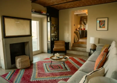 Spacious living room with fireplace, sofa and colourful kilim rug at Villa Santa Maria Nuova, Cortona