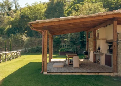 Covered wooden pergola with outdoor dining area and barbecue in the garden of Villa Santa Maria Nuova, Cortona