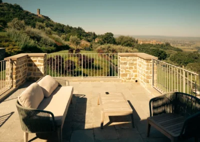 Stone terrace with lounge sofa and armchairs overlooking the Valdichiana valley from Villa Santa Maria Nuova, Cortona