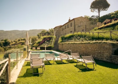 Swimming pool with sun loungers on the terraced lawn of Villa Santa Maria Nuova, a stone villa in the hills of Cortona, Tuscany
