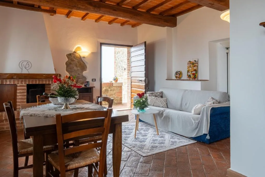 villa-tiberini-torrita-di-siena-apartment-living-dining-fireplace Apartment living and dining area with fireplace, sofa and beamed ceiling