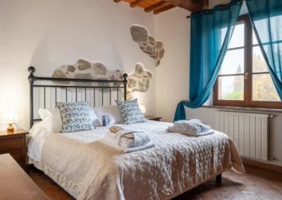 Double bedroom with wrought-iron bed, stone details and beamed ceiling