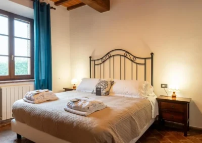 Bright double bedroom with wrought-iron headboard and window onto the countryside