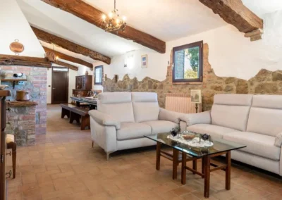 Living room with white sofas, exposed stone wall and beamed ceiling at Villa Tiberini