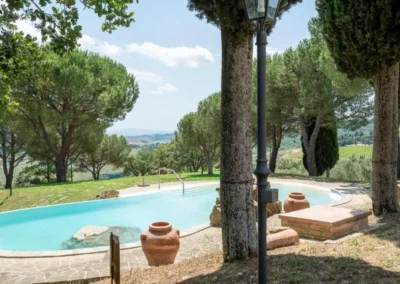 Private pool among umbrella pines and terracotta jars with views over the hills