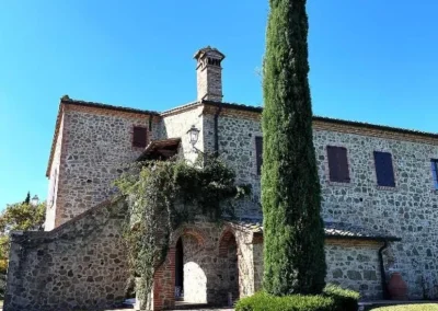 Stone villa with arched entrance, climbing plants and a tall cypress