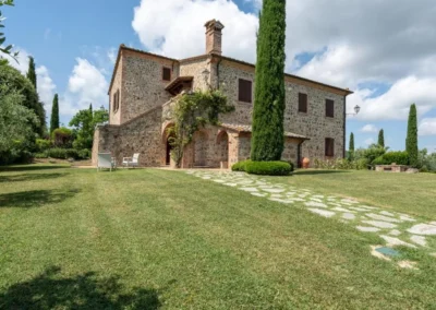 Stone villa facade with tower, climbing roses and lawn at Villa Tiberini Wine Relais