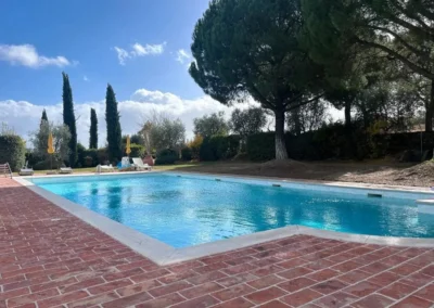 Swimming pool with brick surround, cypresses and umbrella pines at Villa Tiberini Wine Relais